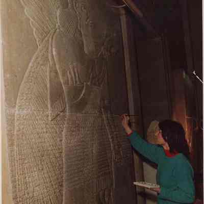 A photo view of a woman working on an old carving. 1/21/1988.