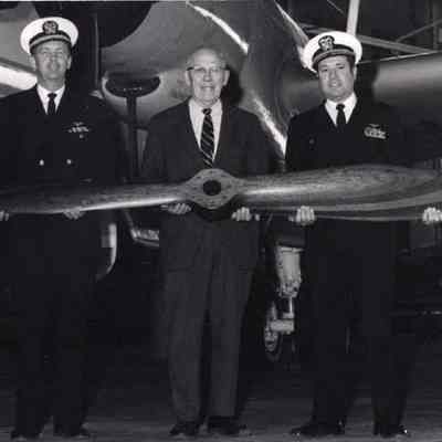 A photo view of 3 men holding a propeller. 3/1/1971