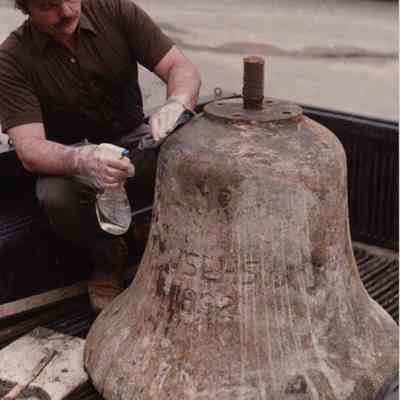 A photo view of a man cleaning a bell shaped object. 5/16/1988.