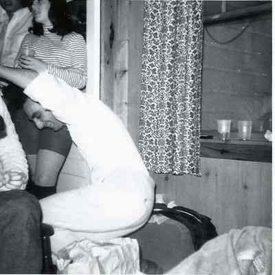A B/W photograph of Gene Gagne falling backwards into a chair.