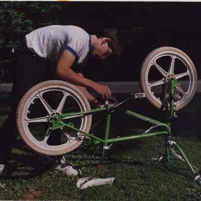 A photo view of a boy repairing his bike. 6/30/1987.