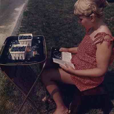 A photo view of a child selling blue berries. 8/16/1988.