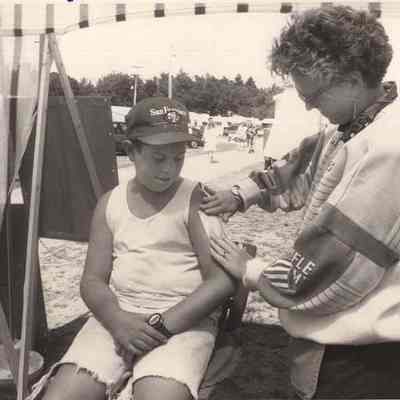 A photo view of a child getting a patch put on.