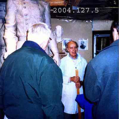 J. Query shows off his clay model of the statue to some people.