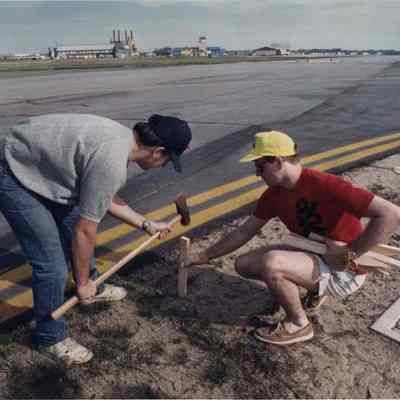 A photo view of two people putting out surveyor stakes. 5/17/1991.