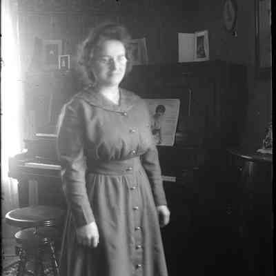 A woman standing in front of a piano.