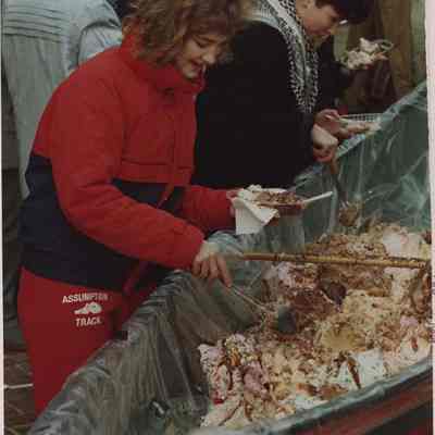 A photo view of 2 people getting food out of a canoe. 2/3/1988.