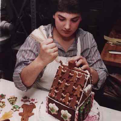 A photo view of a girl making a gingerbread house. 12/23/1986.