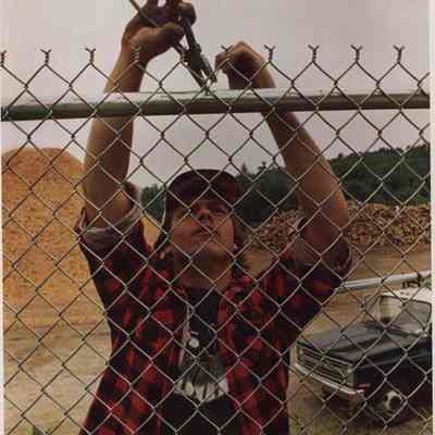 A photo view of a man working on a fence. 7/23/1987.