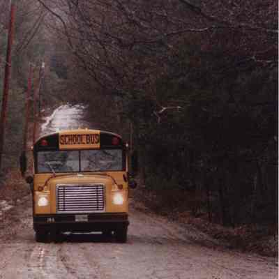 A photo view of a school bus on a gravel road. 5/12/1989.