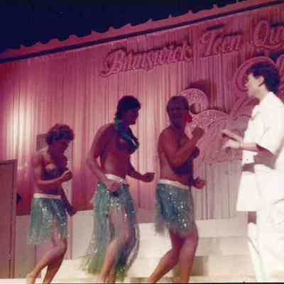 A color photograph of people doing a Hawaiian dance.