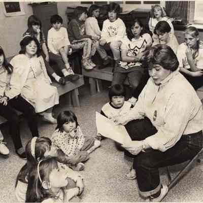 A photo view of Maggie Carle reading to children. 5/15/1992.