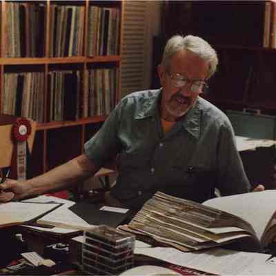 A photo view of a man working at his desk. 8/19/1987.