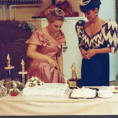 Darby Labbe cutting cake while Katherine Albano is watching.