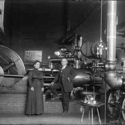 A couple standing in front of a steam engine.