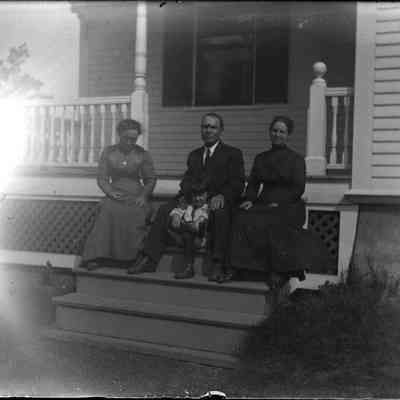 Three people sitting on the door steps.