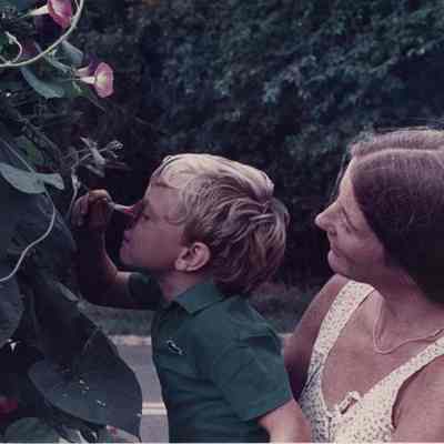 A photo view of a small boy smelling a flower. 8/19/1988.