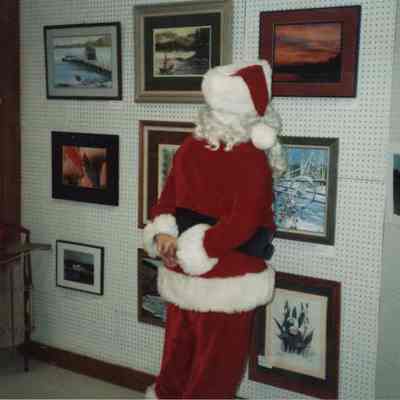 A photo view of Santa Claus looking at art work.