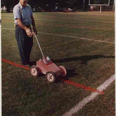 A photo view of a man putting lines on a playing field. 8/28/1987.
