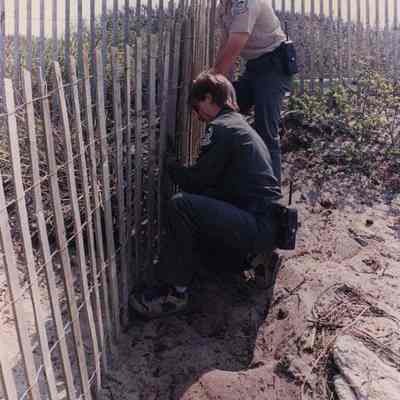 A photo view of two men working on a fence. 5/30/1989.