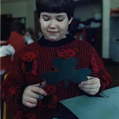 A photo view of a boy cutting out shamrocks. 3/17/1989.