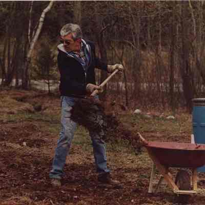 A photo view of a man spreading compost on a garden. 4/29/1988.