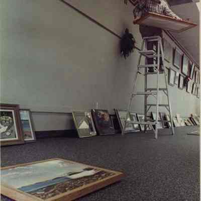 A photo view of a workman hanging pictures. 11/20/1989.