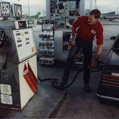 A photo view of a man pumping gas. 7/24/1990.