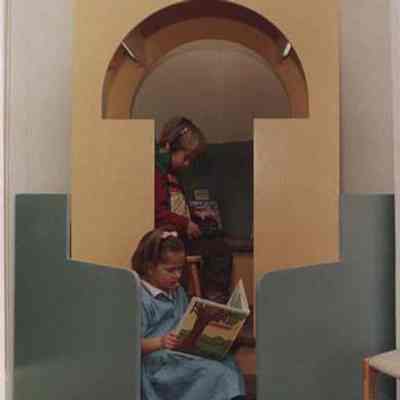 A photo view of 2 children in a library. 4/11/1988.