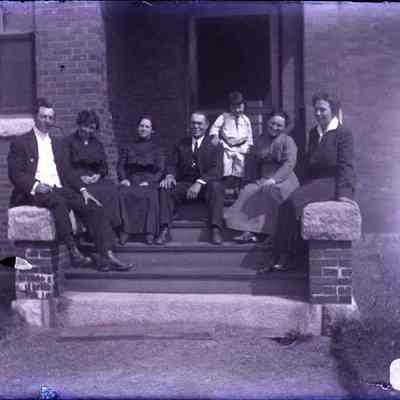 A group of people sitting on the front steps of a building.