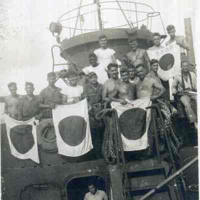 Group of sailors holding Japanese flags.