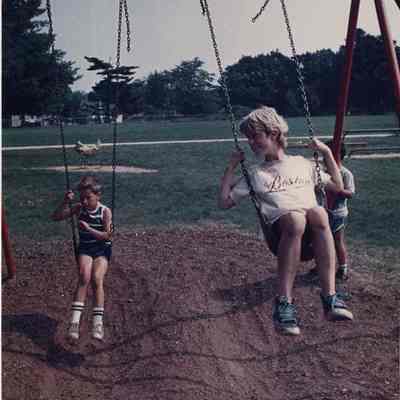 A photo view of children playing on a swing set. 8/9/1988.
