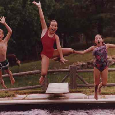 A photo view of 3 children diving into a pool. 7/28/1987.