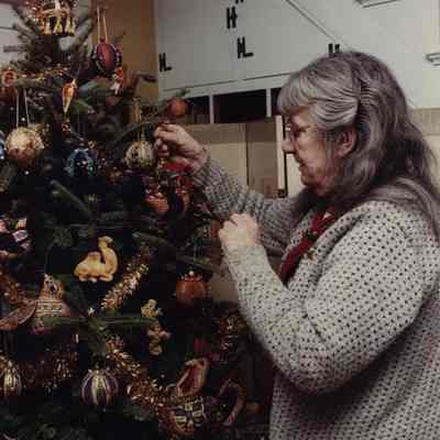A photo view of a lady decorating a Christmas tree. 12/18/1989.