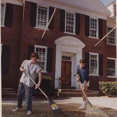 A photo view of raking around a fraternity house at Bowdoin College. 4/28/1988