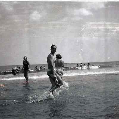 A B/W photograph of some people on a beach.