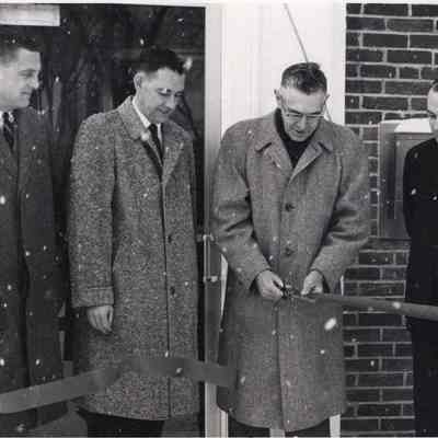 A photo view of 4 men cutting a ribbon.
