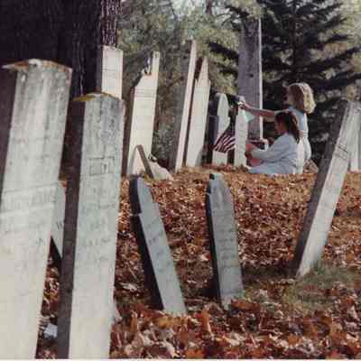A photo view of two children doing a rubbing of a gravestone. 10/27/1989.