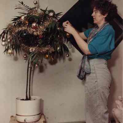 A photo view of a lady decorating a tree. 12/18/1989.