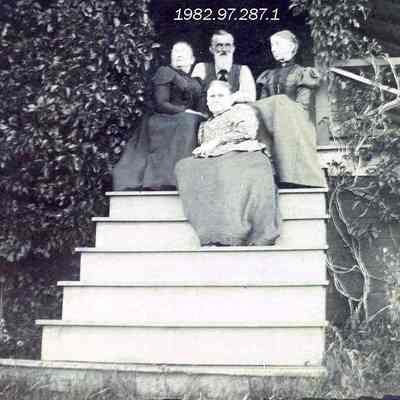 A photo of 4 people sitting on a door step.