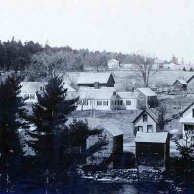 View of Water Street Dennysville from the Edmunds side of the Dennys River. Samuel L. Jones's carpentry shop, which was torn down in 1908, was located beside (to the left of) the blacksmith's shop at the end of this row shops and stores, in this view from the Edmund side of the Dennys River c. 1900.