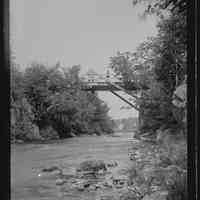          Falls Bridge over the Dennys River, c. 1885; Nineteenth century view of the Falls Bridge over the Dennys River, with several bystanders on the bridge, looking upstream towards houses along the Milwaukee Road in Dennysville visible in the distance.  The photograph was taken by Dr. John P. Sheahan in the 1880's.
   