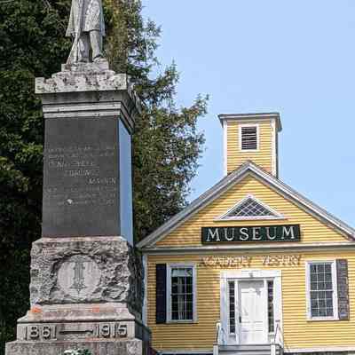 The Soldier's Monument in Dennysville, Maine: The former Dennysville Academy and Church Vestry, now the Academy/Vestry Museum of the Dennys River Historical Society, stands sentinel over the veterans' memorial in 2023.