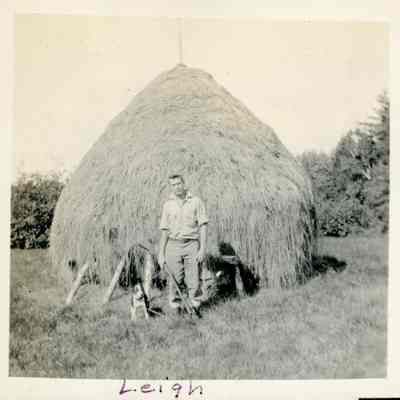 Leigh Gardner and canine friend before a haystack.