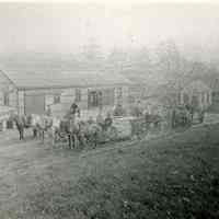          Dennysville Lumber Company, Dennysville Maine, c. 1910; Teamsters prepare to haul several heavy loads of sawn boards for the Dennysville Lumber Company.  Stacks of drying lumber were a common sight along the banks of the Dennys River during the heyday of the lumber industry.  The small square building behind the teams is the Company's office, where records were kept and the men were paid, a reminder of the economic source of the area's stability during the nineteenth and early twentieth centuries.
   