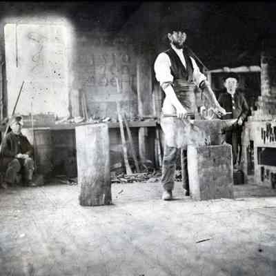 A.L.R. Gardner in his blacksmith shop in Dennysville c. 1880.: Two young spectators watch A.L.R. Gardner at work on his anvil in this view of his blacksmith shop, originally built on the Dennys River by William Kilby in the 1790's.