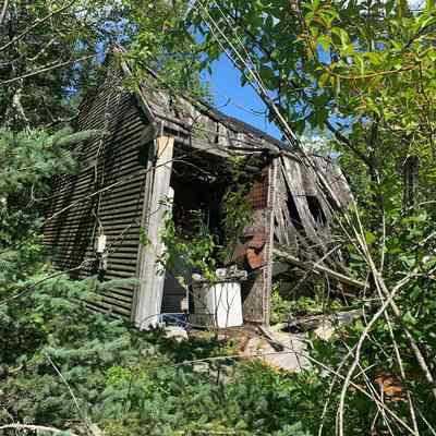 Entrance to the Former Preston District School in 2022: The doorway entrance to the former Preston District Schoolhouse in a sadly dilapidated condition in 2022.  For a number of years it was the one room  dwelling and workshop of Captain Raymond Sprague, a renowned local boatbuilder in Lubec, who retired here to operated a sharpening service he called "Sprague's School of Cutlery."