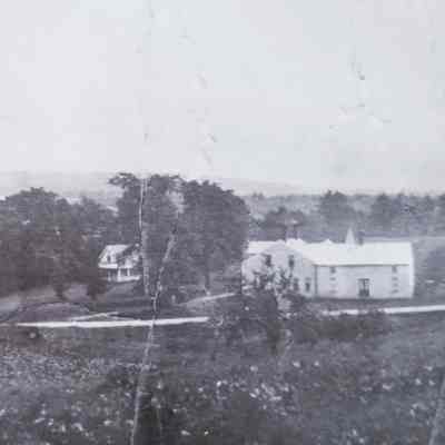 Tarbell's Store, Meddybemps Village, c. 1930: Detail of a Panoramic view of Meddybemps village in the 1930's.  W.E. Tarbell's large store is to the right in the picture.  A Post Office was located in Effie Gillespie's house, from the 1950s through the early 1970s, when it burned. The post office then moved into the Paula Abney house in the village before being relocated in the new Town Hall. Note the carefully plowed field in the left foreground.