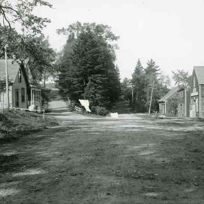Stores at the foot of New Road Hill in Dennysville, Maine.: Frank West's and George Kilby's drug stores were located side by side at the foot of New Road Hill, across from Gardner's stores on Water Street, c. 1900.