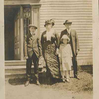 Nellie Lincoln with her parents and brother ready for Church, c. 1914: Nellie stands in front of her parents, Ellen (Jones) and Albert Lincoln, with her brother Albert in front of their farmhouse in Dennysville, Maine.  She wrote along the bottom "Mother, Dad and Albert and I ready for Church."